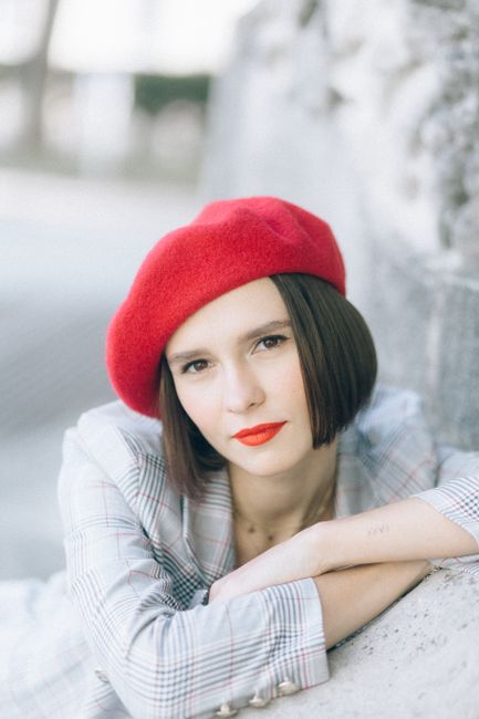 Portrait of a stylish woman wearing a red beret, posing outdoors with a confident expression.