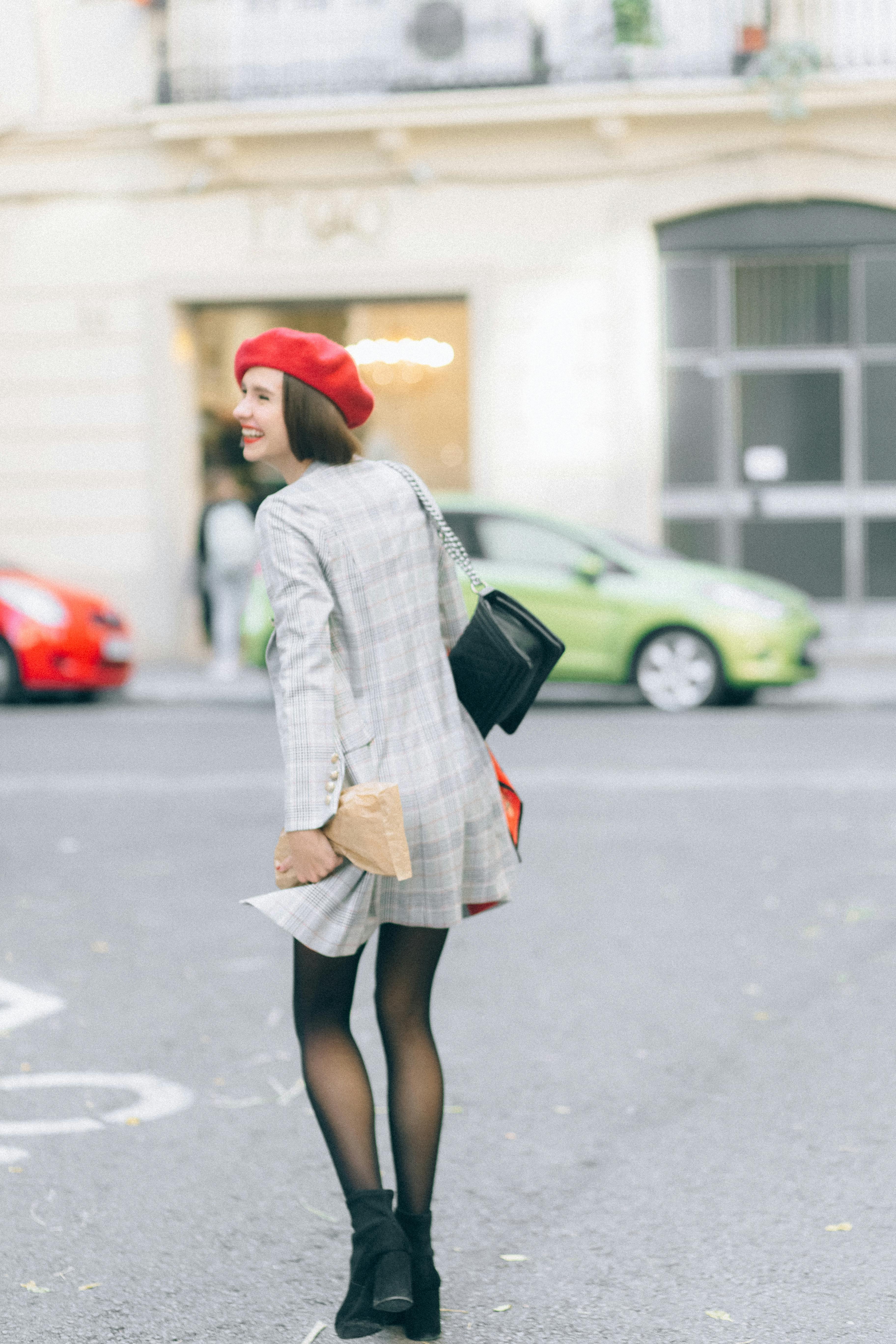 Woman in Gray and White Plaid Coat and Red Hat Standing on Sidewalk · Free Stock Photo