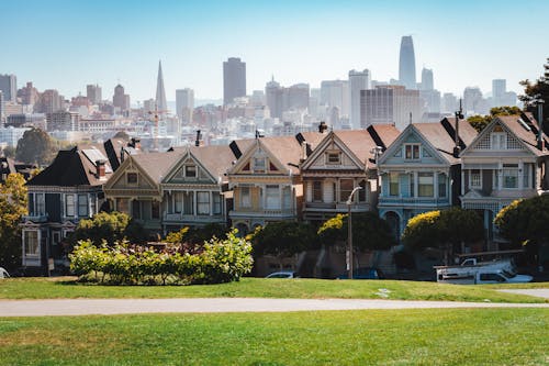 Exterior of typical cozy similar residential houses located in peaceful suburb area of San Francisco against modern skyscrapers on sunny day