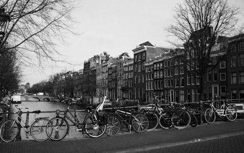 Велосипеды припаркованы на городской набережной возле канала и старых зданий в пасмурный день
