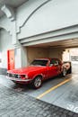 Luxury vintage red coupe car with polished surface and chrome details parked in city street garage on sunny day