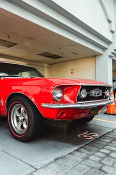 Shiny vintage red car with chrome details parked in street garage on sunny day