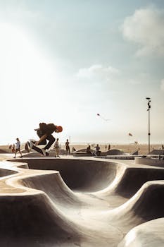 A skateboarder performs a trick in a sunny beach skate park, showcasing dynamic energy and skill.