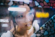 Gentle young Asian woman looking through window