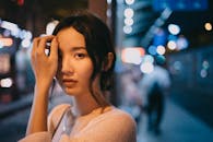Young Asian woman touching face on street