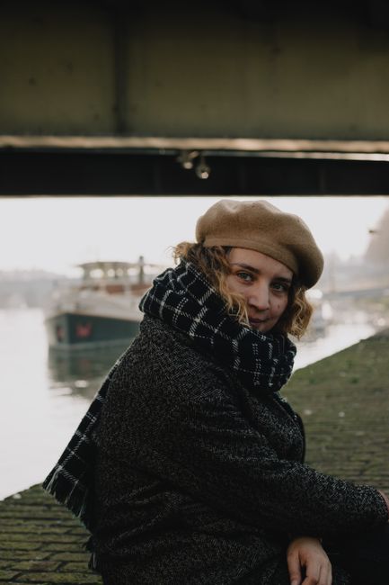 Woman dressed warmly sitting by the riverside in Maastricht on a cool fall day.
