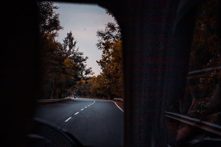 Car Driving Along Road Between Autumn Trees