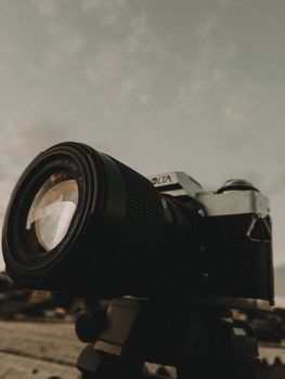 Close-up shot of a vintage camera with a telephoto lens at dusk, creating a moody atmosphere.