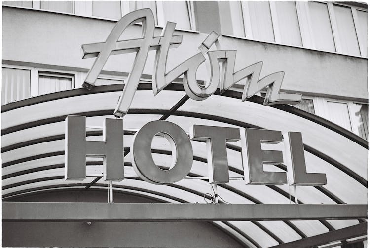 Grayscale Photo Of Atom Hotel Signage