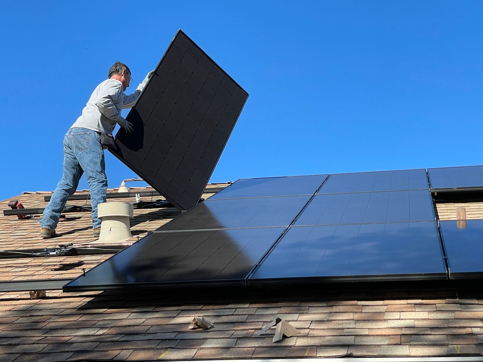A construction worker in protective gear hammering a rooftop panel with precision