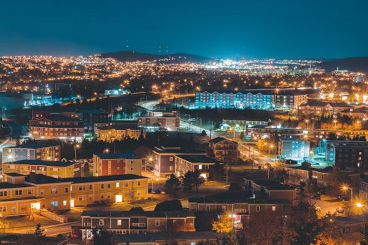 Aerial view of a city at night showcasing vibrant lights and scenic urban architecture.