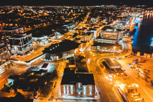 From above of contemporary building exteriors and roadways illuminated by street lights in evening town