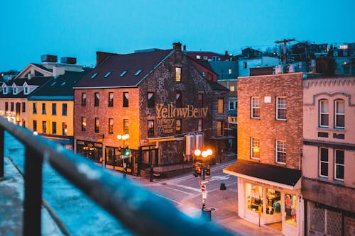 Old masonry house exteriors and roadway with street lights under blue sky in evening town