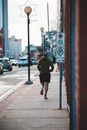 Back view of anonymous male athlete jogging on walkway with road signs during training in town