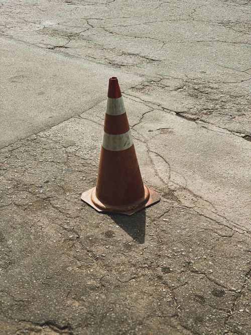 Free Close-up of a traffic cone on cracked pavement, ideal for construction themes. Stock Photo