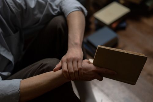 Free Close-up of a person holding a book indoors, emphasizing relaxed reading and contemplation. Stock Photo