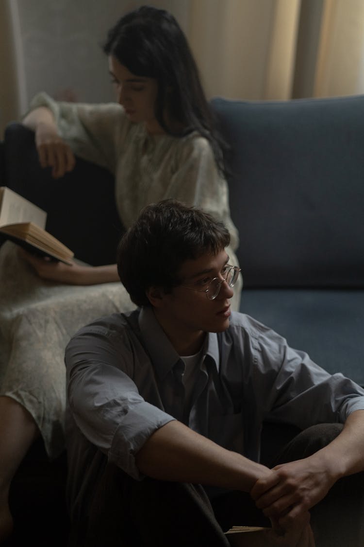 Man In Gray Button Up Shirt Sitting On The Floor Near The Couch 