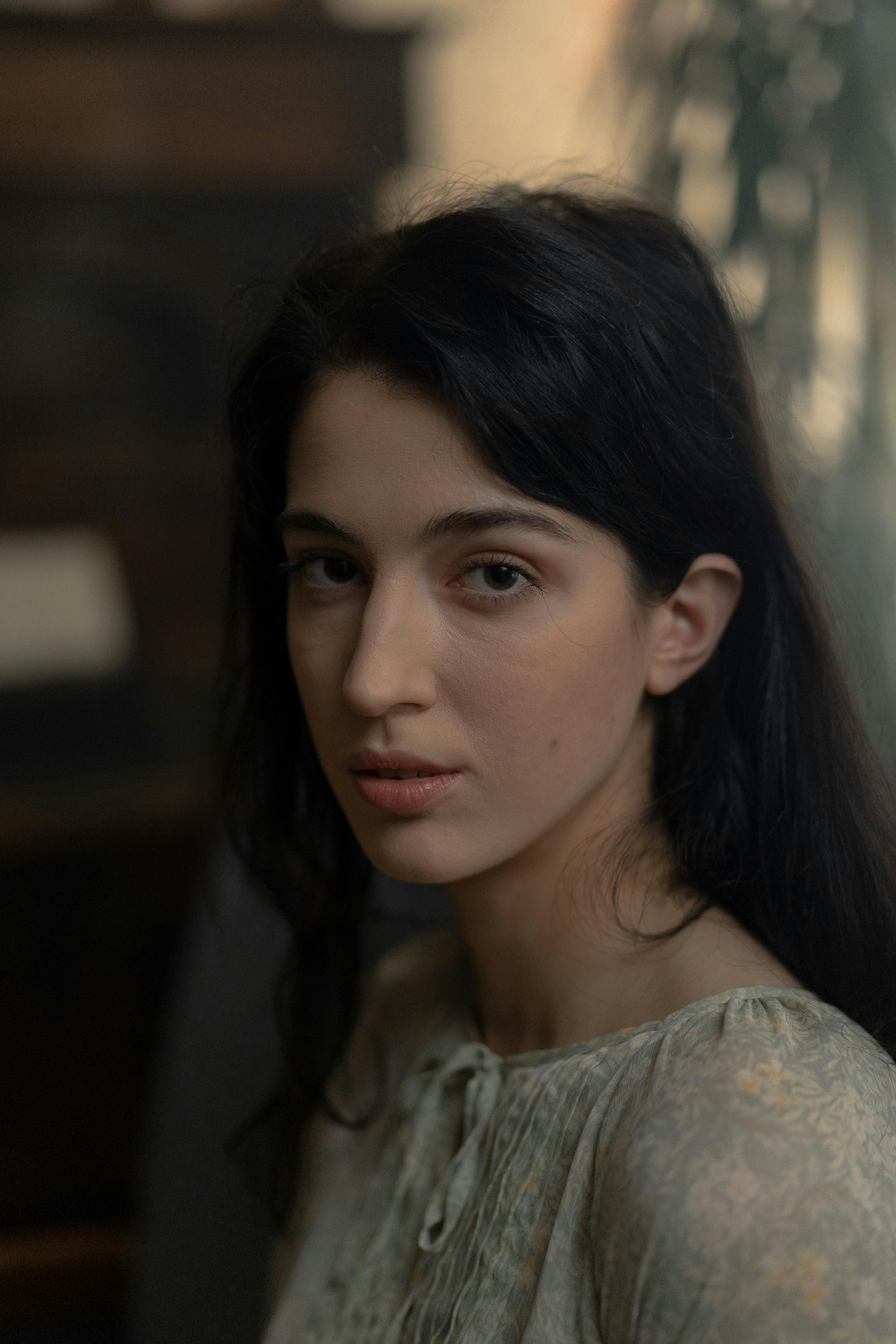 A serene and elegant portrait of a young woman with dark hair, gazing softly at the camera.