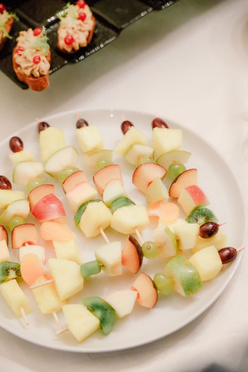 Free Colorful fruit skewers featuring apples, kiwis, and grapes on a white plate. Perfect for healthy eating. Stock Photo