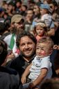 Positive ethnic man carrying son with painted Syrian flag and Arabic lettering on face at opposition rally