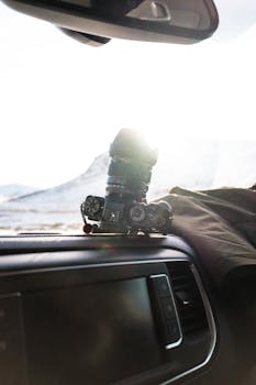 Camera on a car dashboard with sun glare, capturing scenic outdoor view.