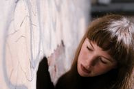 Crop dreamy adolescent near graffiti wall in city