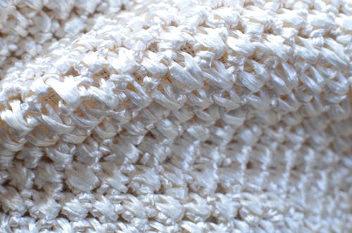Textured backdrop of bright knitted beige textile with seamless pattern and glowing surface