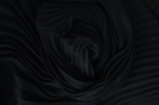 Top view of abstract background representing wavy creased black silk fabric in twilight