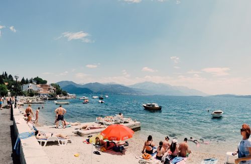 Free A lively beach scene with sunbathers, boats, and distant hills under clear blue skies. Stock Photo