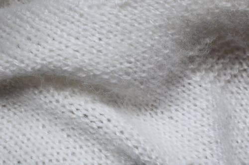 Top view textured abstract background of white knitted woolen textile placed on table