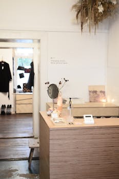 Stylish interior design of modern light clothes store or atelier studio with wooden counter and changing room