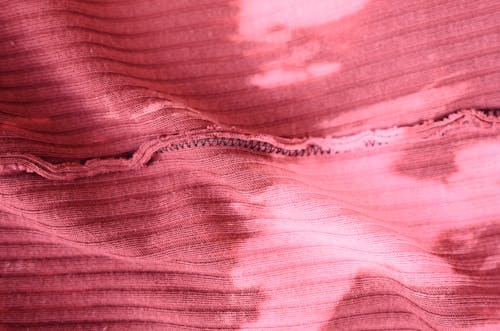 Top view pink knitted fabric with stains and inside seam placed on table