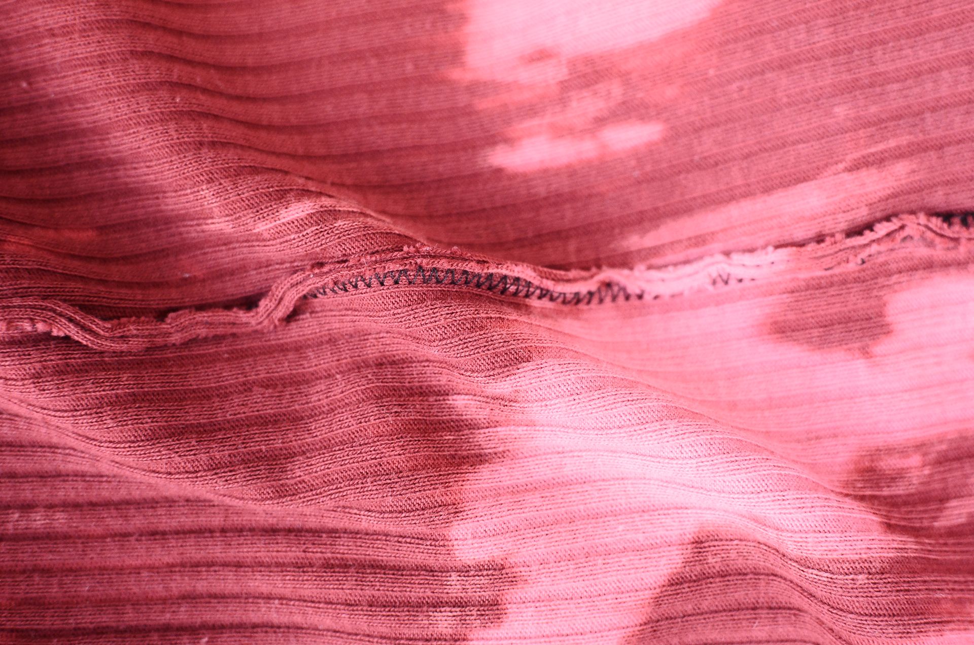 Top view pink knitted fabric with stains and inside seam placed on table