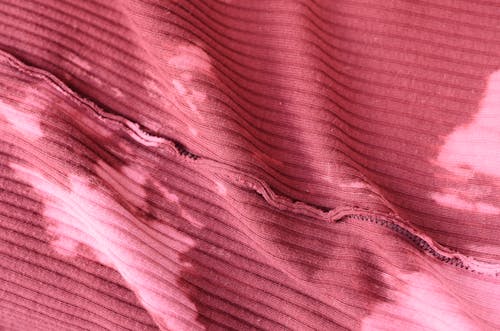 Top view abstract background of pink knitted textile with stains placed on table inside out