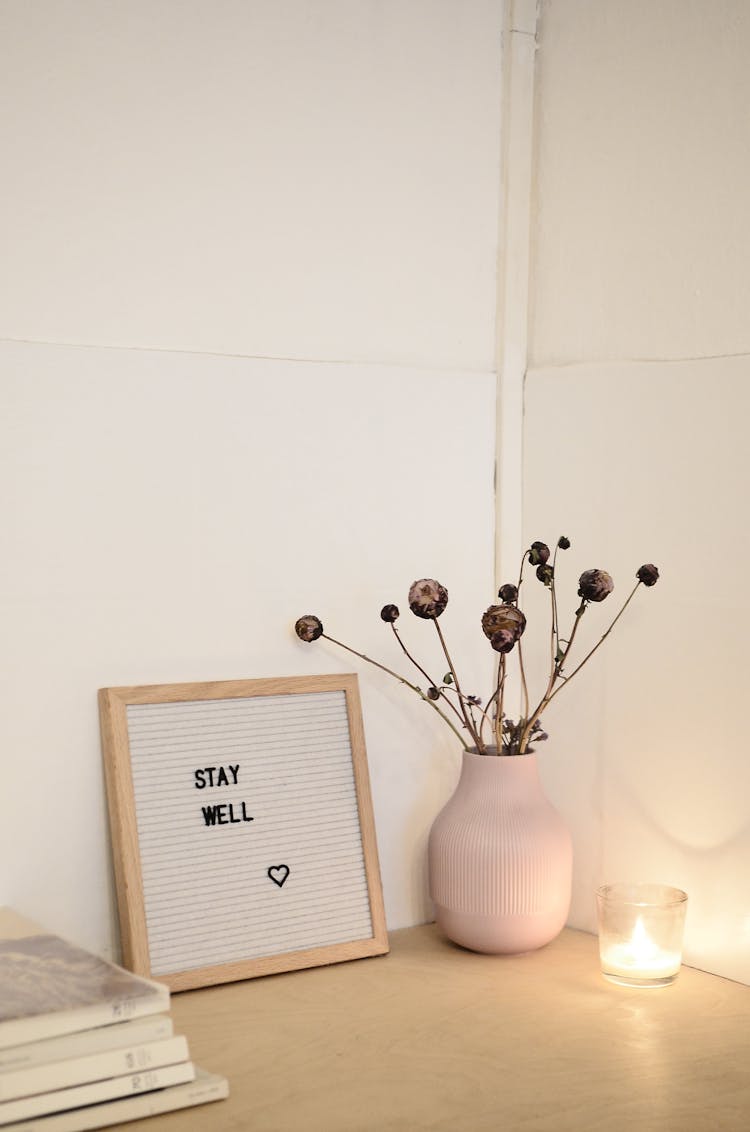 Stack Of Books Near Frame And Dry Plants In Vase