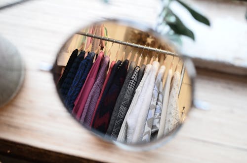 Clothes hanging on rack in reflection of mirror