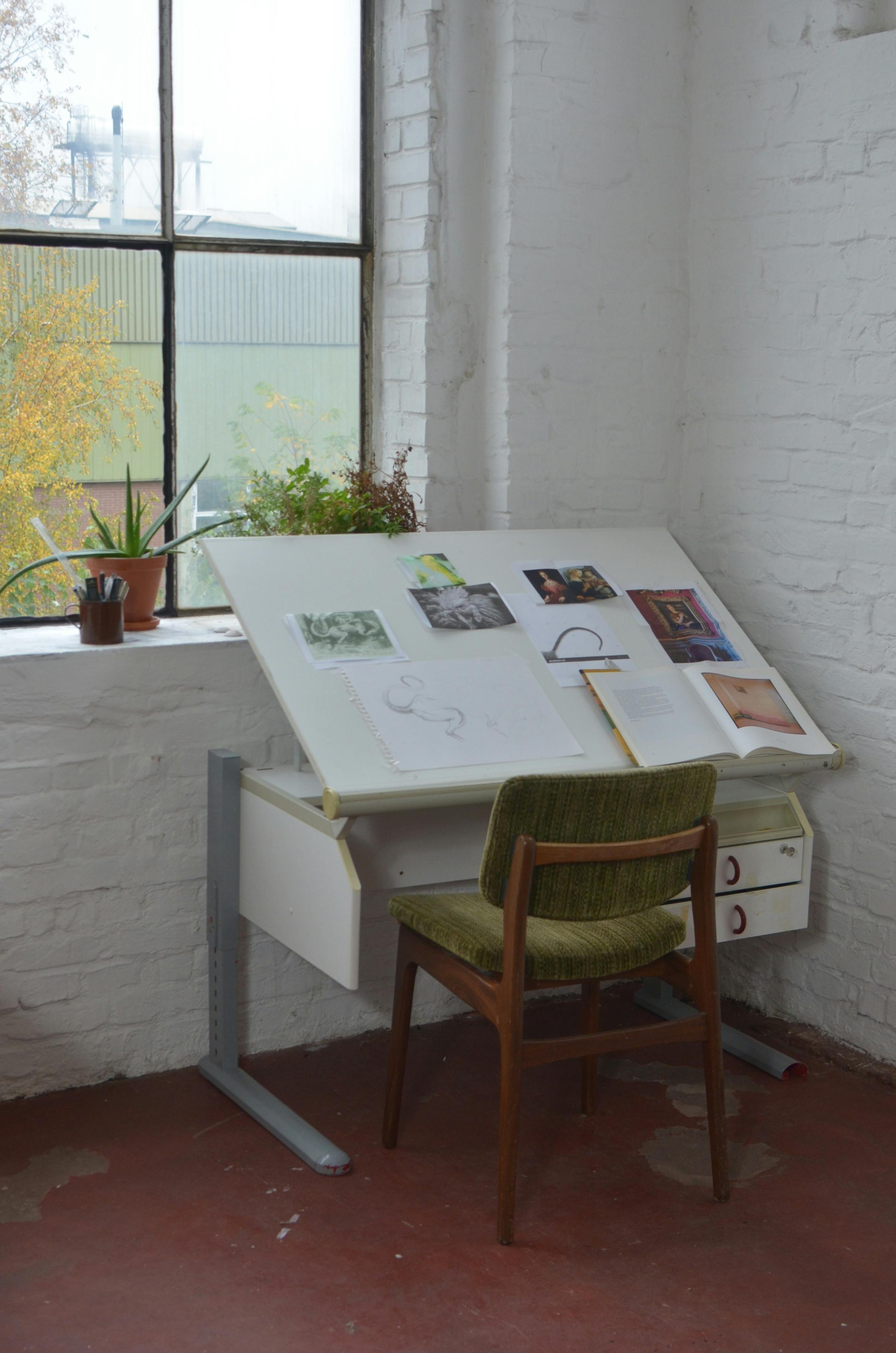 chair placed near window and table with drawings