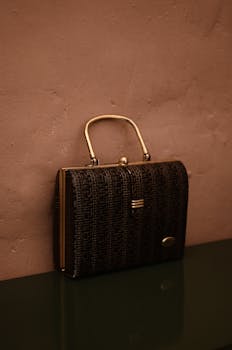 Vintage bag with golden handle placed on reflecting surface as accessory for garment