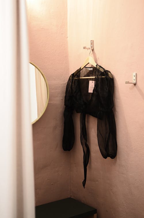 Interior of room for trying clothes on with mirror and blouse on wall