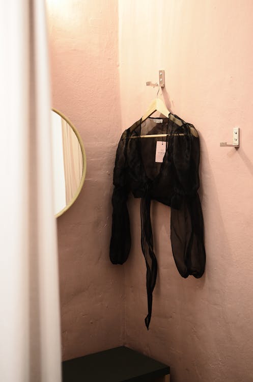 Interior of room for trying clothes on with mirror and blouse on wall