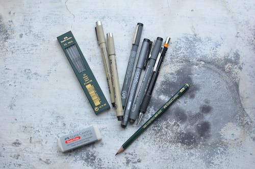 Top view of different pens and markers placed on shabby gray table for drawing