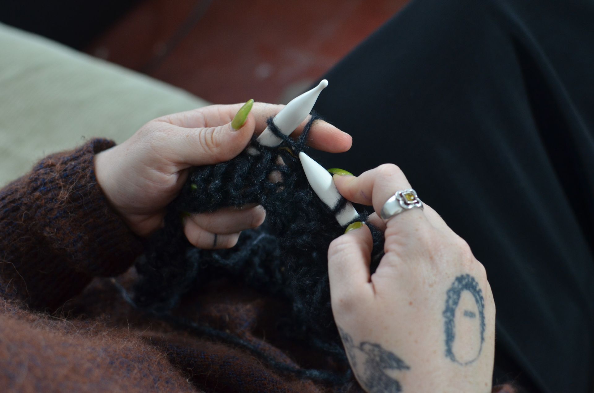 Detailed shot of hands knitting a soft woolen fabric, highlighting craftsmanship and cozy feel.