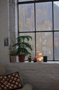 Warm and inviting loft space featuring a candlelit window sill, plants, and cozy decor.