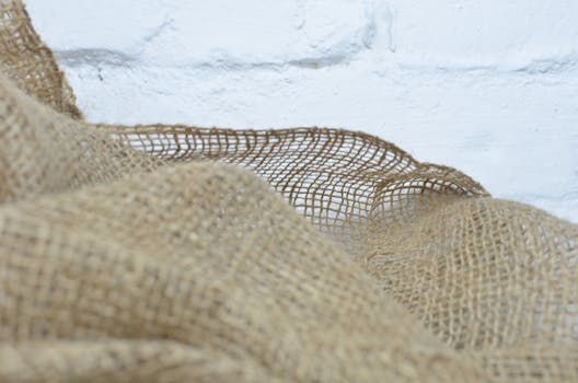 Close-up of natural burlap fabric with white background, highlighting texture and eco-friendly theme.