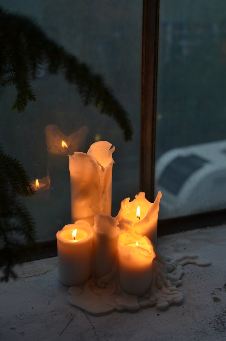 Bright Wax Candles Reflecting In Window At Night