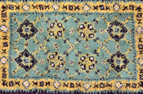 Textured soft warm oriental styled carpet with symmetric geometric ornament as abstract background