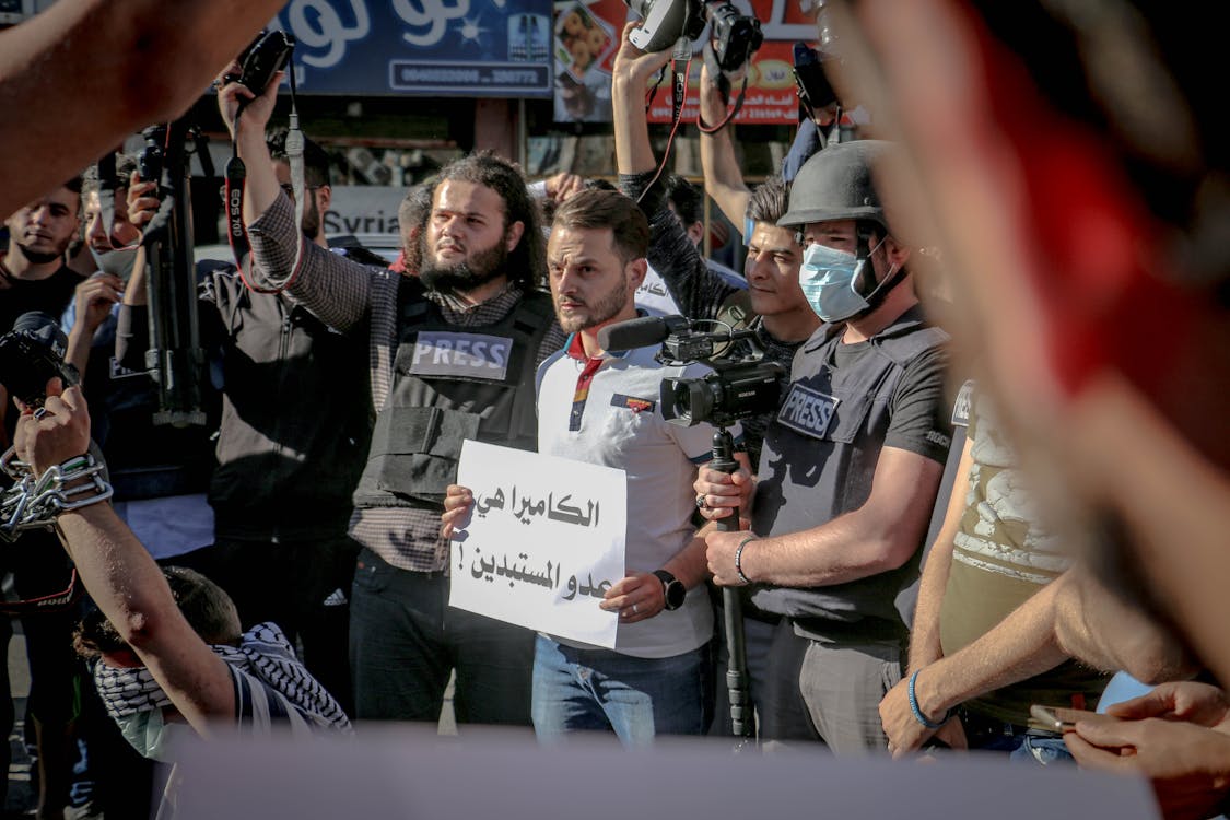 Free Group of ethnic journalists with placard with Arabic inscription and cameras at demonstration against policy Stock Photo