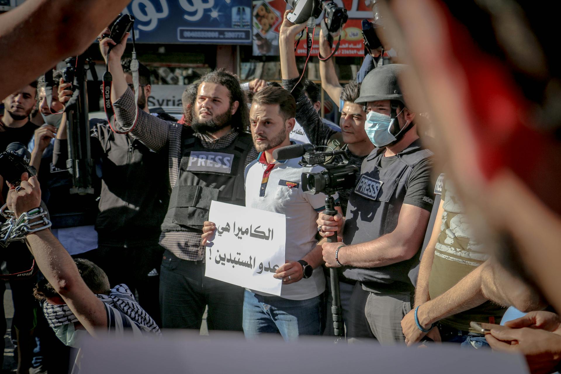 Group of ethnic journalists with placard with Arabic inscription and cameras at demonstration against policy