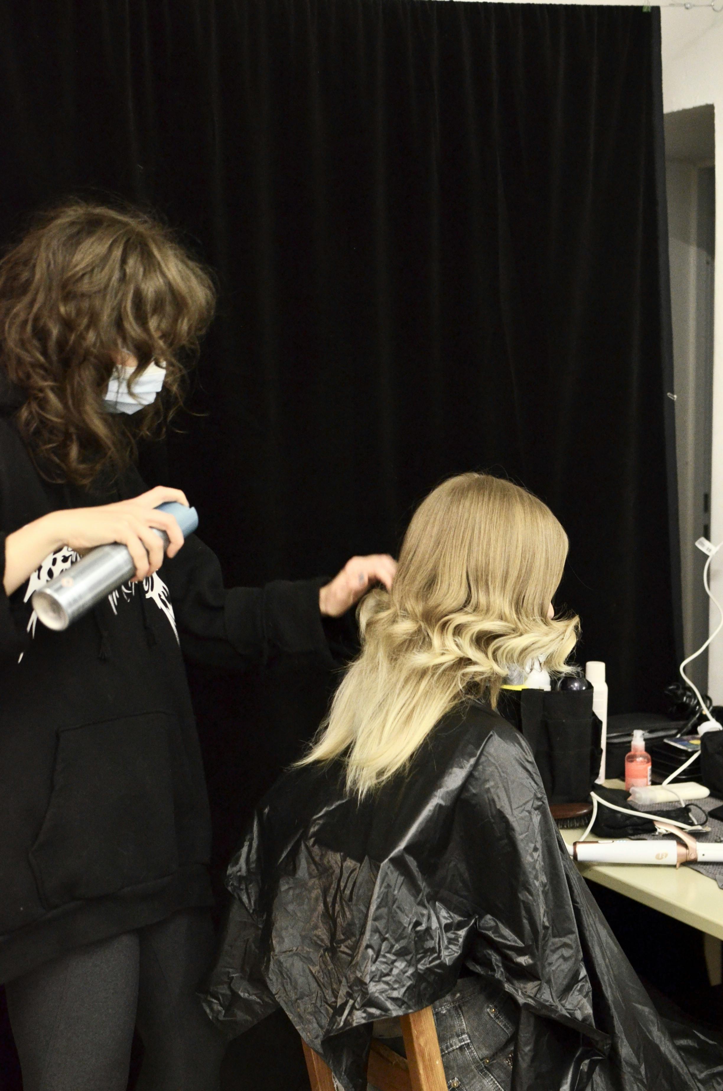 hairdresser making hairdo for client in dressing room