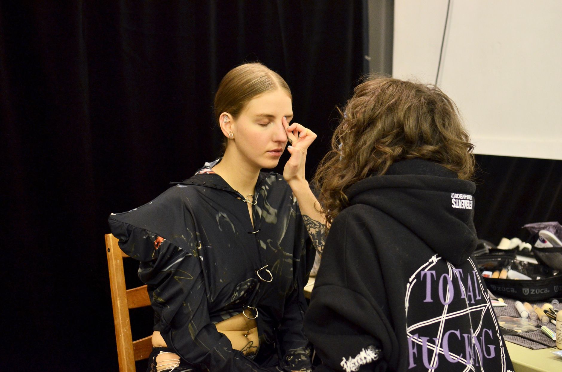 Female stylist applying foundation on face of model during preparation for photo session